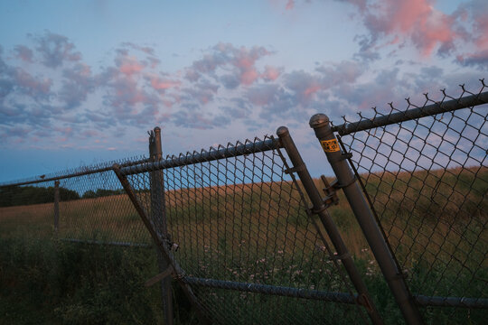 A slanted chain-link fence under a colorful evening sky in Hadley, Massachusetts