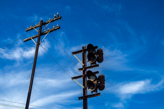Vintage railway signal and wooden telegraph pole with ceramic insulators stands under a bright blue sky with light clouds in Brazil. 
