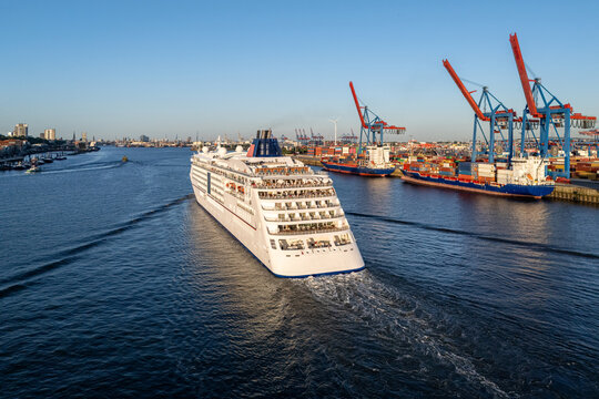 Aerial view of the cruise ship sailing past the Ovelgonne waterfront with container terminals and cranes in the background in Hamburg, Hamburg, Germany.