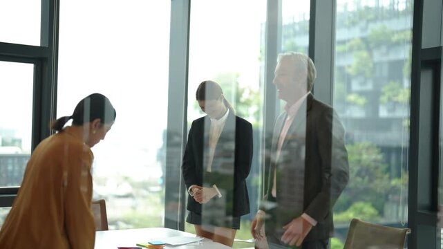 Through glass shot of business partners shaking hands after successful negotiation with sales representative. Corporate agreement, partnership successful deal.
