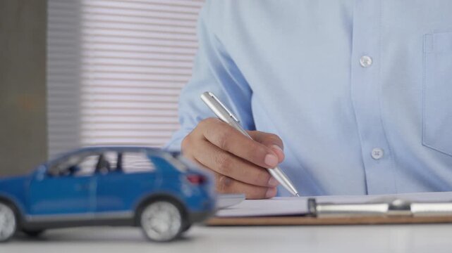 Customer are reading and signing auto insurance claim form After Vehicle Accident with Damaged Car Model, Personal Protection Coverage and Risk Management Concept, Drivers and Insurance Services