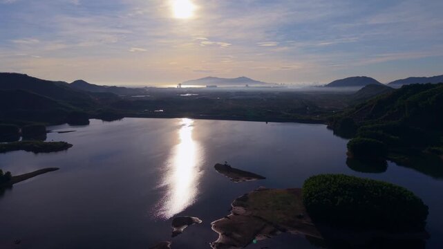 Cinematic aerial drone footage of sunrise over Da Nang coastline and cityscape in central Vietnam. Golden morning light illuminating beaches, mountains and urban landscape.