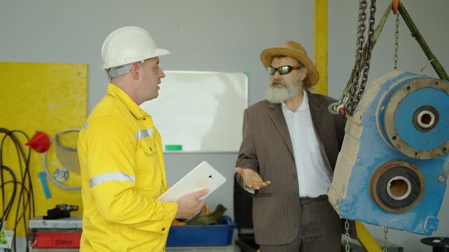 Disgruntled factory manager in a suit has a heated argument with a subordinate in a yellow uniform, reprimanding him for poor work quality before angrily storming out of the industrial warehouse