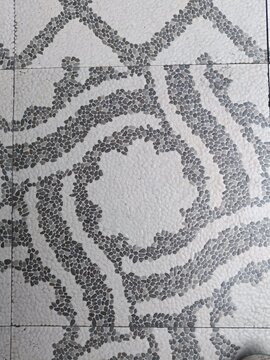 Decorative pebble mosaic floor tiles with black and white swirling pattern, elegant natural stone texture for interior design and architecture
