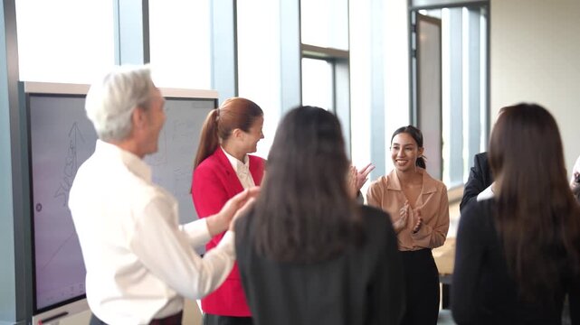 Business professionals celebrate outstanding team performance after reaching company targets during corporate meeting. Leadership recognition, employee achievement and workplace collaboration concept.