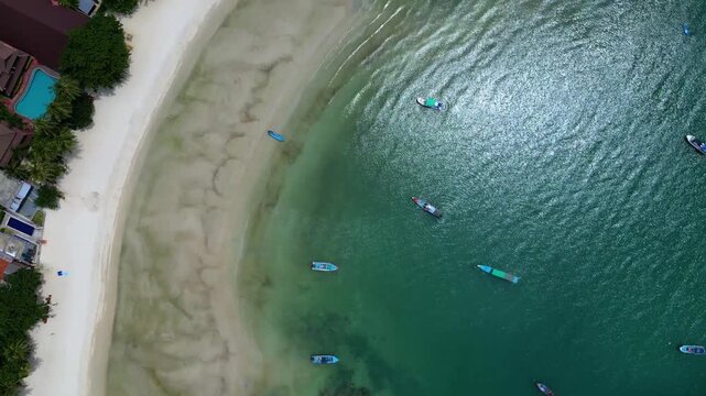 Aerial top-down drone footage of Thong Nai Pan Beach in Koh Phangan, Surat Thani, Thailand. The video shows a bird&rsquo;s-eye view of the tropical coastline, white sand beach, turquoise sea, and surroundin