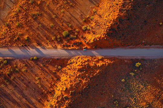Aerial view of a vehicle driving on a dirt road through the arid landscape of Lake Machattie near Bedourie, Queensland, Australia.