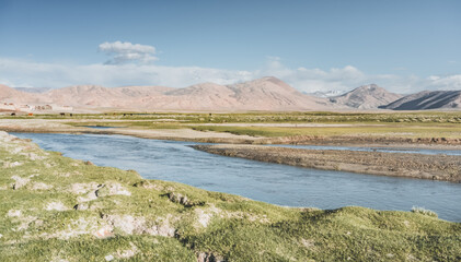 Clear-water rivers and lakes in a mountain valley, pastures and green grassy fields set against mountain ranges and snow-capped, glacier-clad peaks—a scenic landscape background © Denis