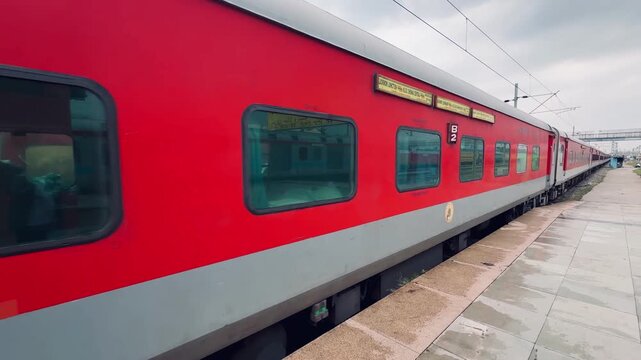 Red Indian Railways passenger train coach stationed at a railway platform, illustrating rail travel, public transportation, and modern Indian railway infrastructure.