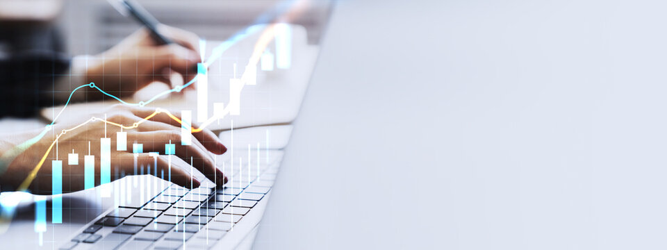 Hands typing on laptop with glowing financial trading charts and currency graph overlays illustrating market analysis and growth trends.