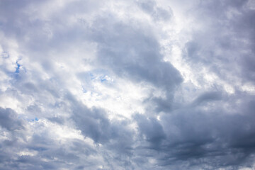 Fototapeta premium Blue Sky with Thick Layered Rain Clouds and Dramatic Weather. A textured blue sky partially covered by thick gray rain clouds creating an impressive dramatic weather scene. Perfect natural background 
