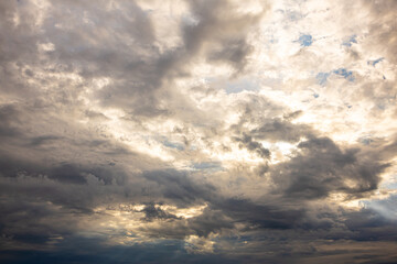 Obraz premium Moody Stormy Sky with Heavy Dark Clouds and Sunlight. Heavy storm clouds illuminated by soft sunlight create an impressive dramatic sky. Perfect for weather forecasts, climate, environmental themes