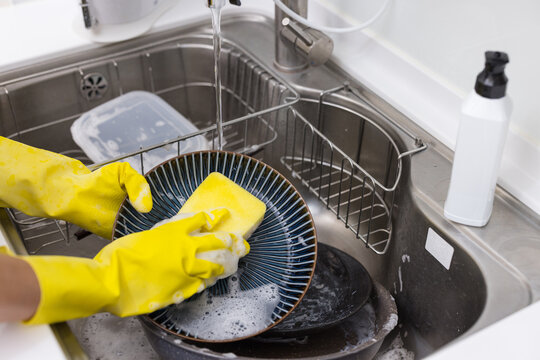 Person cleaning dishes in kitchen sink