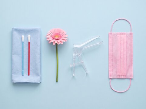 Medical gynecological exam tools and protective mask on blue background