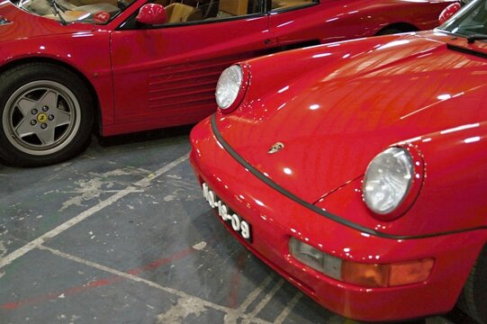 Red Porsche and Ferrari classic luxury sportscars in garage