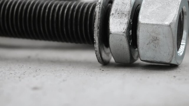 Macro close-up of a threaded steel bolt with nut and washer. Industrial fastener used in construction, engineering, manufacturing and heavy equipment assembly.