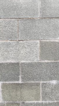 Gray Granite Stone Block Wall Texture. Close-up pan of a textured wall built from rectangular gray granite stone blocks with prominent mortar joints. Video transition, 4k, 60 fps