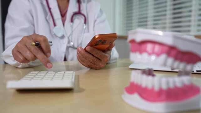 Dentist using calculator to estimate medical bills, insurance coverage, and medication costs in a clinic. Concept of healthcare finance, budgeting, and affordable dental care.