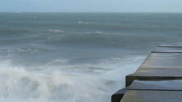 Crashing ocean wave spray against concrete pier