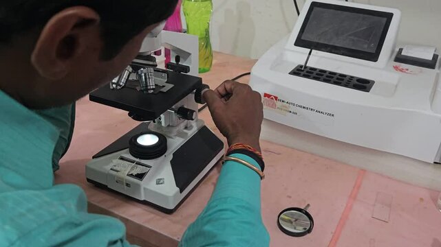 Scientist examining laboratory sample using optical microscope in modern research laboratory. Researcher focusing on microscopic analysis, scientific observation, laboratory diagnostics