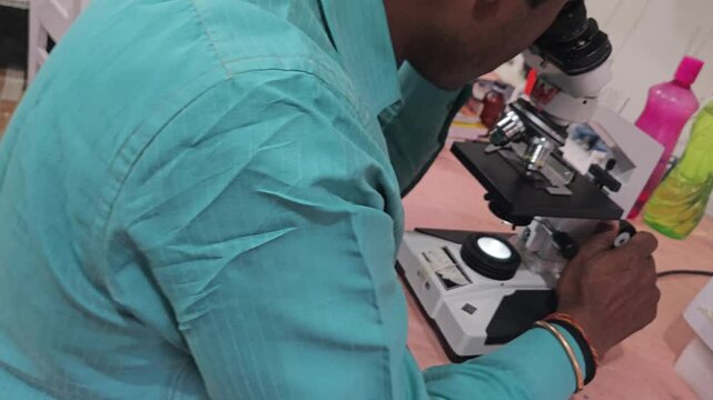 Scientist examining laboratory sample using optical microscope in modern research laboratory. Researcher focusing on microscopic analysis, scientific observation, laboratory diagnostics