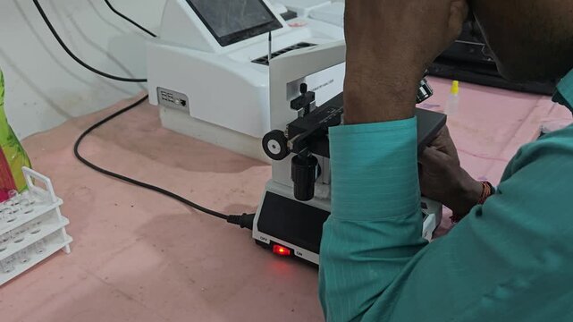 Scientist examining laboratory sample using optical microscope in modern research laboratory. Researcher focusing on microscopic analysis, scientific observation, laboratory diagnostics