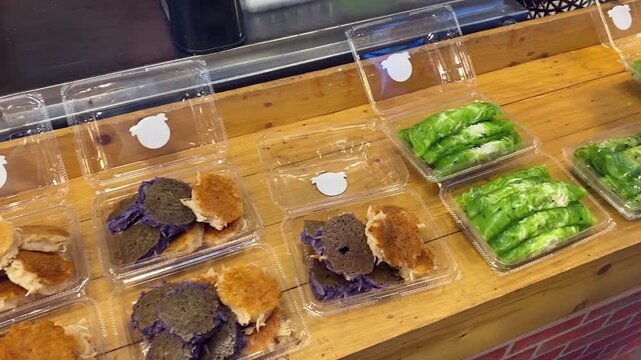 Thai Desserts Displayed at Asian Open Street Food Market in Bangkok. Colorful Green & Purple Sweet Coconut Rice Pudding Pancakes (Khanom Babin) For Sale