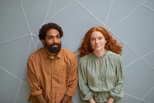 Styled portrait of a mixed couple seated against minimalist geometric string wall for lifestyle portrait and relationship banner background