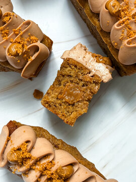 Top view closeup of cut mini loaf cake showing moist texture and caramel core. Flat lay of rectangular pastry slice surrounded by chocolate frosted cakes.