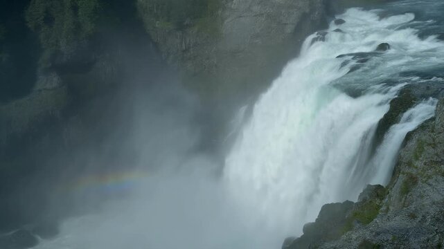 Powerful waterfall with a faint rainbow appearing in the mist