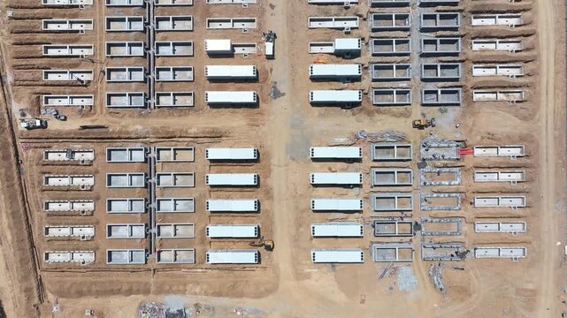Aerial view of a battery energy storage station construction site with modular units and concrete foundations