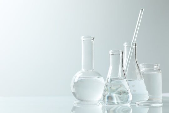 Laboratory glassware containing a clear liquid, placed on a mirrored surface against a white background