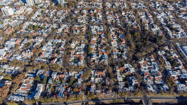 Mendoza, Argentina - 11 June 2022: Aerial view of the residential neighborhoods of Mendoza, featuring dense tree canopy, terracotta rooftops, and grid-patterned streets under clear daylight.
