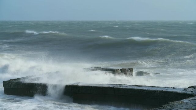 Crashing waves on dark stone formations under a stormy sky