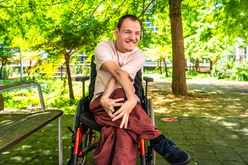 Naklejka premium Smiling man with cerebral palsy in wheelchair enjoying park