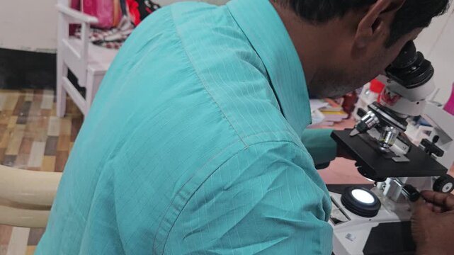 Scientist examining laboratory sample using optical microscope in modern research laboratory. Researcher focusing on microscopic analysis, scientific observation, laboratory diagnostics