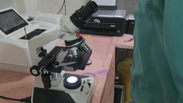Scientist examining laboratory sample using optical microscope in modern research laboratory. Researcher focusing on microscopic analysis, scientific observation, laboratory diagnostics