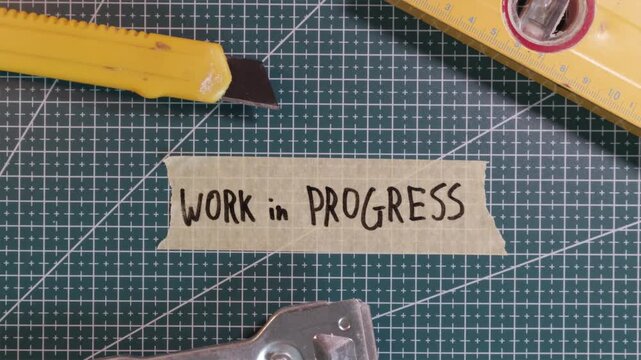 Top down view of applying WORK IN PROGRESS tape sticker on green mat.