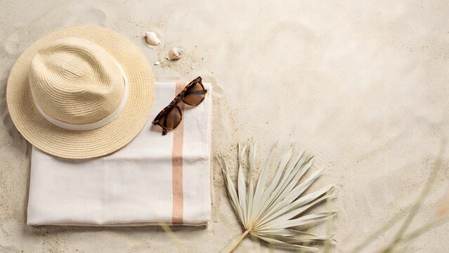 Minimal beach arrangement with towel and hat with copy space &ndash; Suitable for summer sale banners, magazine covers, or luxury travel agency advertisements.