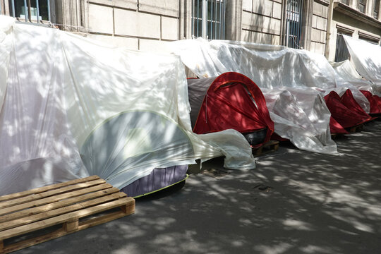 Camp de tentes de sans-abri install&eacute;es &agrave; l'ombre le long d'un fa&ccedil;ade sur le trottoir