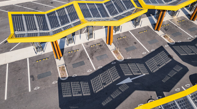 Saulce-sur-Rhone, France - 24 June 2026: Aerial view of a Fastned electric vehicle charging station with a distinctive yellow solar-panel canopy and parking bays.