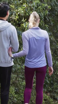 Vertical video: Beginning walk couple linking arms showing affection man draping hoodie arm on path