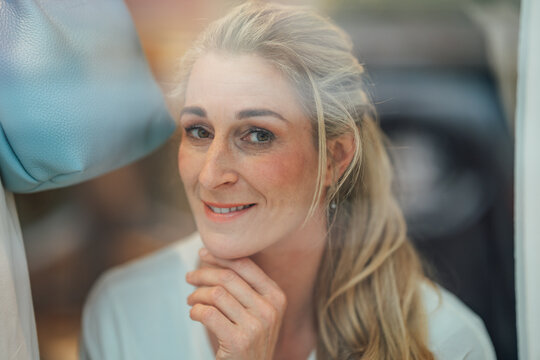 Blonde woman enjoying window shopping at a luxury fashion store with beautiful reflections and modern city lifestyle.