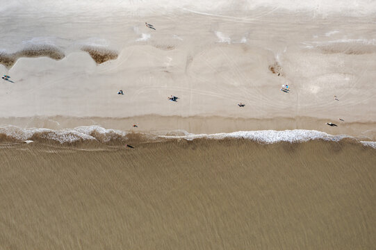 Jekyll Island, Georgia, United States - 31 December 2021: Aerial view of the sandy beach and ocean waves with people walking along the shoreline at Jekyll Island.