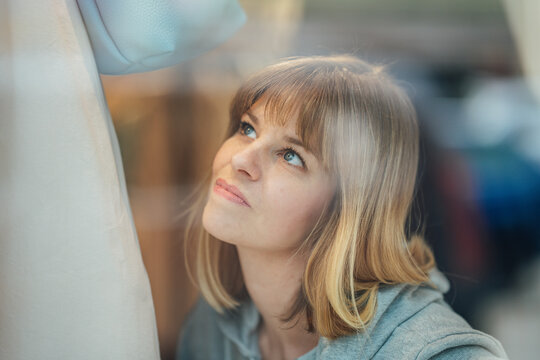 Portrait of a fashionable blonde woman by a luxury store window with elegant reflections and sophisticated urban atmosphere.