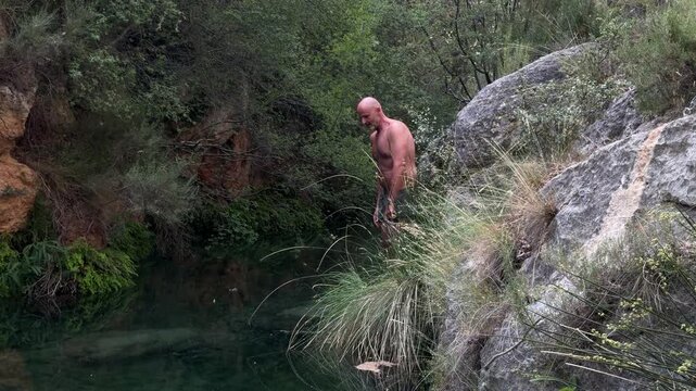 Mature adult man jumping into a natural pool