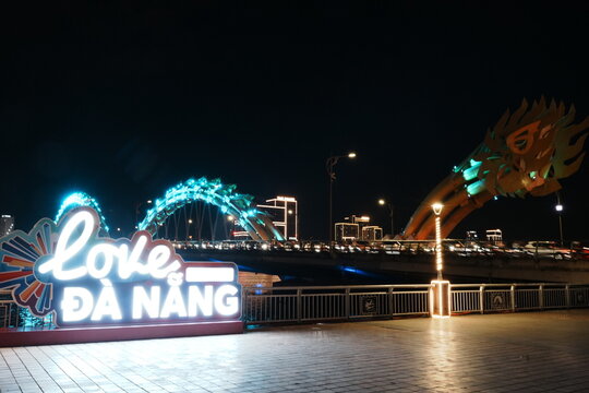 Dragon Bridge illuminated at night over Han River in Da Nang, Vietnam, featuring vibrant night city reflections and "I Love Da Nang" - ベトナム ダナン 夜空に輝くドラゴンブリッジ ハン川の美しく映る夜景 I Love Da Nangのイルミネーション