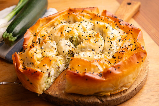 Golden baked savory filo pie with zucchini and feta cheese, sprinkled with black sesame seeds