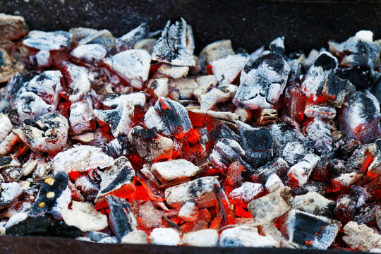 Detailed and Atmospheric Close-up Photograph of Red Smoldering Coals inside a Traditional Fireplace