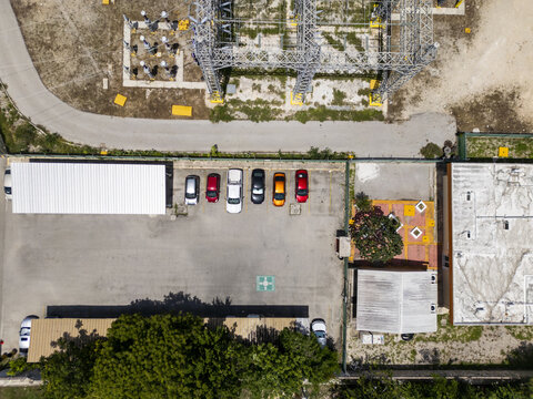Aerial view of CFE SE Norte electrical substation facility in Merida, featuring a parking lot with several cars, surrounding trees, and industrial infrastructure, Merida, Yucatan, Mexico.